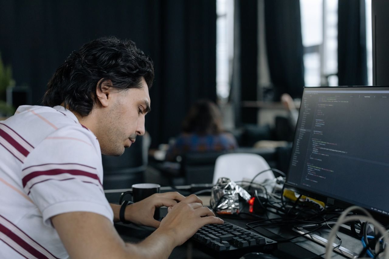 Mastering the First Impression: Your intriguing post title goes here A coder intensely typing at a workstation in a contemporary office setup.