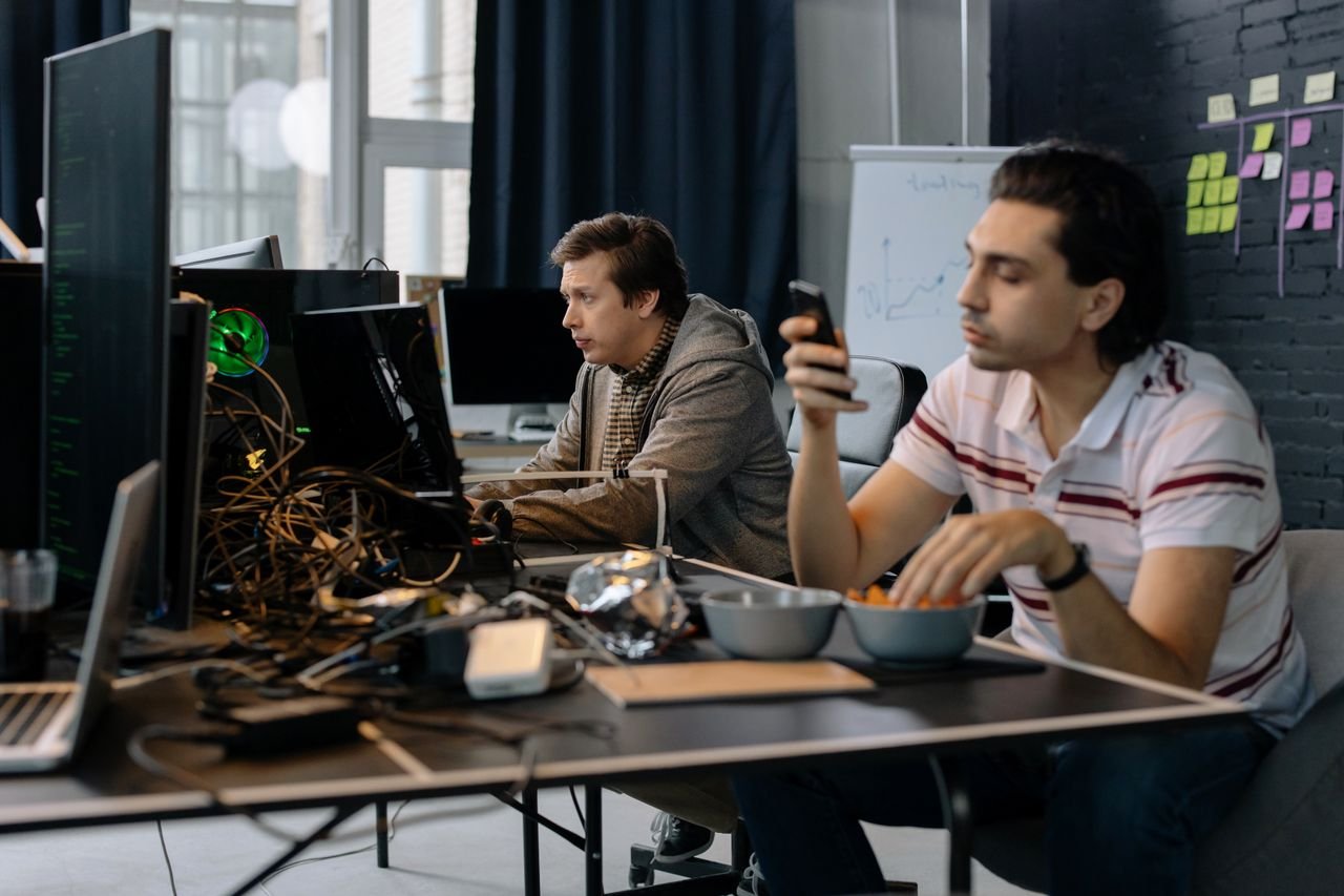 The Art of Drawing Readers In: Your attractive post title goes here Two men working in a modern office setup, focused on technology and collaboration.